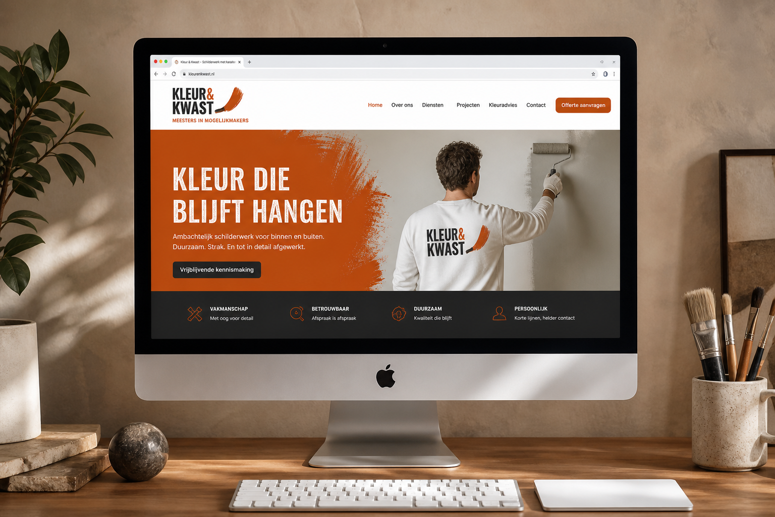 Voorbeeld kluswebsite Kleur & Kwast op iMac — oranje huisstijl, eigen logo en domein
